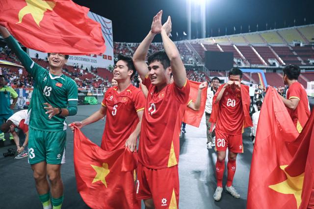 Vietnam's players celebrate after their victory in the men's football final match between Thailand and Vietnam during the 33rd Southeast Asian Games (SEA Games) at Rajamangala National Stadium in Bangkok on December 18, 2025. (Photo by Lillian SUWANRUMPHA / AFP)