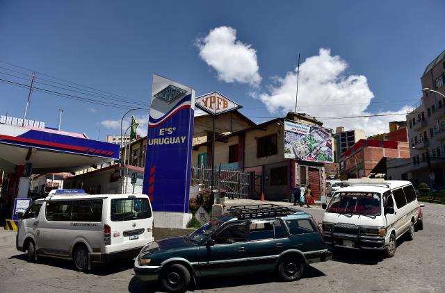 Vehicles queue at a petrol station to get fuel in La Paz on December 18, 2025. Bolivia's President Rodrigo Paz announced on December 17, 2025, the country will get rid of its fuel subsidies, ending 20 years of fixed prices under the Latin American nation's previous leftist leaders. (Photo by Jorge BERNAL / AFP)