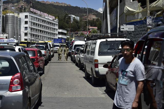 Two soldiers walk among vehicles queueing at a petrol station to get fuel in La Paz on December 18, 2025. Bolivia's President Rodrigo Paz announced on December 17, 2025, the country will get rid of its fuel subsidies, ending 20 years of fixed prices under the Latin American nation's previous leftist leaders. (Photo by Jorge BERNAL / AFP)