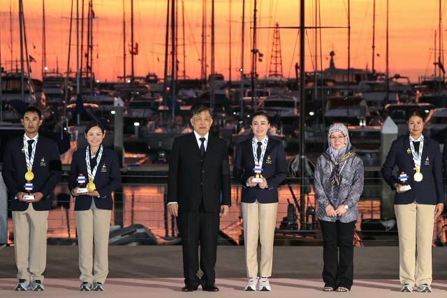 This pool photo taken and released on December 18, 2025 shows Thailand's King Maha Vajiralongkorn posing with Queen Suthida and other gold medallists of the mixed keelboat SSL47 sailing event during the 33rd Southeast Asian Games (SEA Games) at the Ocean marina yacht club in Chonburi province. (Photo by POOL / AFP)