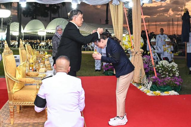 This pool photo taken and released on December 18, 2025 shows Thailand's King Maha Vajiralongkorn presenting the gold medal to Queen Suthida after her victory in the mixed keelboat SSL47 sailing event during the 33rd Southeast Asian Games (SEA Games) at the Ocean marina yacht club in Chonburi province. (Photo by POOL / AFP)