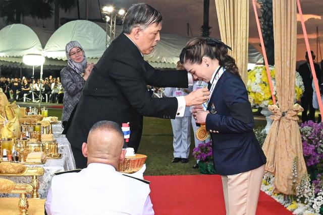 This pool photo taken and released on December 18, 2025 shows Thailand's King Maha Vajiralongkorn presenting the gold medal to Queen Suthida after her victory in the mixed keelboat SSL47 sailing event during the 33rd Southeast Asian Games (SEA Games) at the Ocean marina yacht club in Chonburi province. (Photo by POOL / AFP)