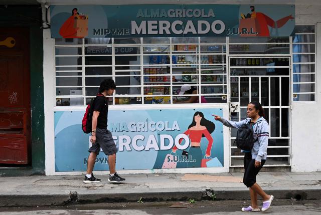 People walk past a grocery store in Havana on December 18, 2025. (Photo by YAMIL LAGE / AFP)