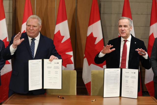 Canadian Prime Minister Mark Carney (R) and Premier of Ontario Doug Ford pose for a photo after signing a Co-operation Agreement between Ontario and Canada on Environmental and Impact Assessment during a news conference on Parliament Hill December 18, 2025 in Ottawa, Canada. (Photo by Dave Chan / AFP)