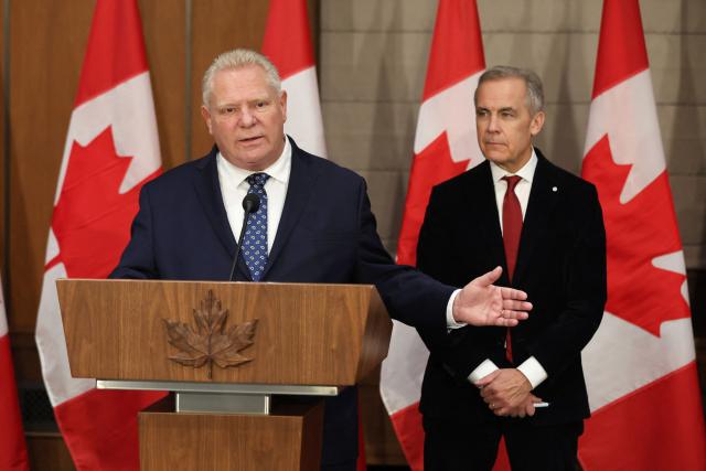 Canadian Prime Minister Mark Carney (R) listens as Premier of Ontario Doug Ford speaks during a news conference on Parliament Hill, December 18, 2025 in Ottawa, Canada. (Photo by Dave Chan / AFP)
