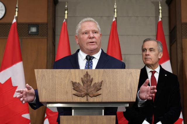 Canadian Prime Minister Mark Carney (R) listens as Premier of Ontario Doug Ford speaks during a news conference on Parliament Hill, December 18, 2025 in Ottawa, Canada. (Photo by Dave Chan / AFP)