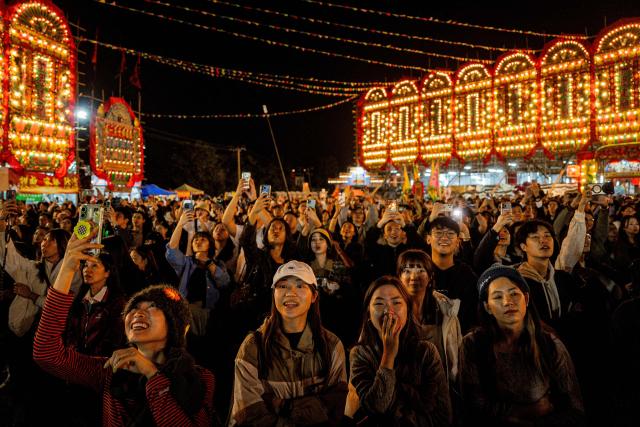 People watch a paper effigy of the Ghost King being paraded during the decennial Jiao Festival of Kam Tin in Hong Kong on December 18, 2025. The Taoist ritual, held once every ten years, is performed to give thanks to deities, ward off misfortune and pray for peace and prosperity in the community. (Photo by Leung Man Hei / AFP)