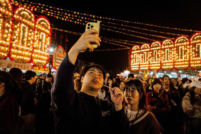People watch a paper effigy of the Ghost King being paraded during the decennial Jiao Festival of Kam Tin in Hong Kong on December 18, 2025. The Taoist ritual, held once every ten years, is performed to give thanks to deities, ward off misfortune and pray for peace and prosperity in the community. (Photo by Leung Man Hei / AFP)
