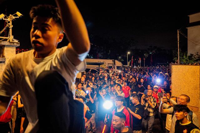 People watch a paper effigy of the Ghost King being paraded during the decennial Jiao Festival of Kam Tin in Hong Kong on December 18, 2025. The Taoist ritual, held once every ten years, is performed to give thanks to deities, ward off misfortune and pray for peace and prosperity in the community. (Photo by Leung Man Hei / AFP)