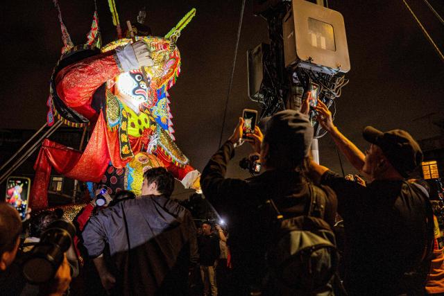 People take photos of a paper effigy of the Ghost King as it is paraded during the decennial Jiao Festival of Kam Tin in Hong Kong on December 18, 2025. The Taoist ritual, held once every ten years, is performed to give thanks to deities, ward off misfortune and pray for peace and prosperity in the community. (Photo by Leung Man Hei / AFP)