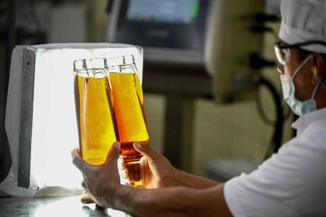 A worker checks bottles at the Santa Teresa rum factory in La Victoria, Aragua state, Venezuela, on December 17, 2025. (Photo by Federico PARRA / AFP)