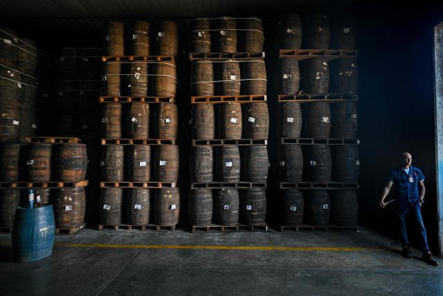 An employee stands next to rum barrels stored in an aging warehouse at the Santa Teresa rum factory in La Victoria, Aragua state, Venezuela, on December 17, 2025. (Photo by Federico PARRA / AFP)