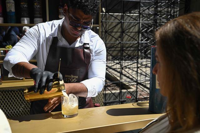 A bartender prepares a drink during an event by Hacienda Santa Teresa rum producer in Caracas on December 13, 2025. (Photo by Federico PARRA / AFP)