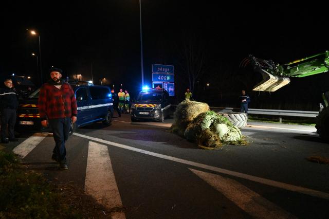 Pierre Guillaume Mercadal (L), leader of the "coordination rurale"  (CR 82) take part in a blockage of the A20 motorway as farmers protest against the government's mandatory culling protocol for cattle herds affected by lumpy skin disease (dermatose nodulaire contagieuse) near Montauban, southwestern France, on December 18, 2025. The main farming unions will be received on December 19, 2025 by French Prime Minister, who oversaw the latest announcements on managing the lumpy skin disease (LSD) "dermatose nodulaire contagieuse" outbreak, which sparked the resurgence of farmers anger fueled by the EU-Mercosur agreement. (Photo by Matthieu RONDEL / AFP)