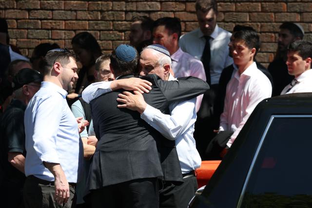 Mourners hug after the funeral of Boris and Sofia Gurman, who were killed in the December 14 Bondi Beach shooting attack, at the Sydney Chevra Kadisha in Sydney on December 19, 2025. Father-and-son gunmen are accused of firing into crowds at a beachside Jewish festival on December 14, killing 15 in an attack authorities linked to "Islamic State ideology". (Photo by DAVID GRAY / AFP)
