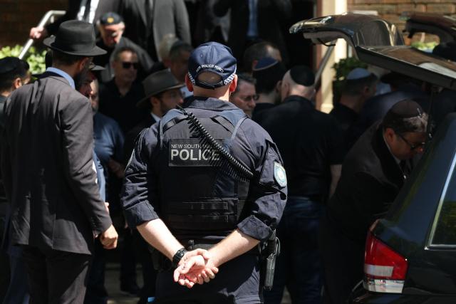 A police officer stands guard after the funeral of Boris and Sofia Gurman, who were killed in the December 14 Bondi Beach shooting attack, in Sydney on December 19, 2025. Father-and-son gunmen are accused of firing into crowds at a beachside Jewish festival on December 14, killing 15 in an attack authorities linked to "Islamic State ideology". (Photo by DAVID GRAY / AFP)