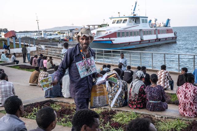 A lottery ticket vendor walks among people in a square along the shores of Lake Tana in Bahir Dar on December 9, 2025. Northern Amhara is Ethiopia's second most populated region with roughly 23 million inhabitants, and has endured nearly three years of conflict between the federal army and the "Fano," Amhara's self-defence militias.
The present conflict stems from the 2020-2022 Tigray War, which killed more than 600,000 people, according to the African Union.
The Fano, like many in Amhara, felt betrayed by the November 2022 peace deal after their support to the government against the neighbouring Tigrayan forces.
It came to a head in April 2023, when an attempt by the federal government to disarm the Fano and Amhara forces ignited the conflict. (Photo by Marco Simoncelli / AFP)