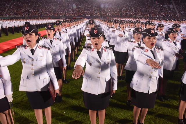 Female police officers take the oath during the graduation ceremony of nearly 5,000 new noncommissioned officers of the National Police at the Ueno Defensores del Chaco stadium in Asuncion on December 18, 2025. The ceremony was led by Paraguay's President Santiago Pena, together with Interior Minister Enrique Riera Escudero and the National Police Commander, Carlos Benitez, and included the symbolic awarding of diplomas, the oath of the new noncommissioned officers, and messages from the main national authorities. (Photo by DANIEL DUARTE / AFP)