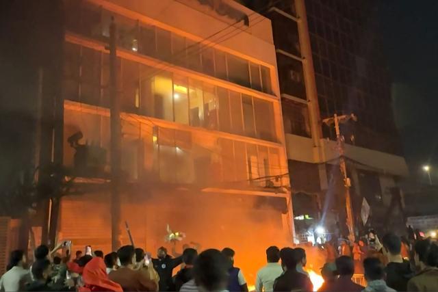 This frame grab from AFPTV video footage taken on December 19, 2025 shows smashed windows and a fire outside the Prothom Alo office in Dhaka, amid protests following the news of the death of youth leader Sharif Osman Hadi. Violence broke out in Bangladesh's capital early December 19 after a youth leader of the country's 2024 pro-democracy uprising who was injured in an assassination attempt died in a hospital in Singapore. Several buildings in the capital, including those housing the country's two leading newspapers, were set on fire, according to authorities, with staff trapped inside. (Photo by Maruf Hasan / AFPTV / AFP)