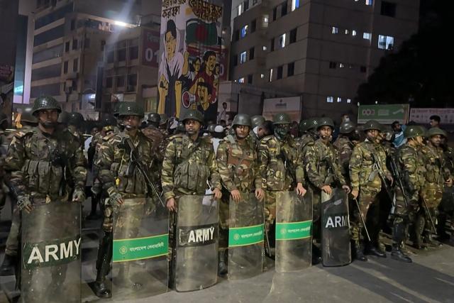 This frame grab from AFPTV video footage taken on December 19, 2025 shows military personnel standing guard in Dhaka, amid protests following the news of the death of youth leader Sharif Osman Hadi. Violence broke out in Bangladesh's capital early December 19 after a youth leader of the country's 2024 pro-democracy uprising who was injured in an assassination attempt died in a hospital in Singapore. Several buildings in the capital, including those housing the country's two leading newspapers, were set on fire, according to authorities, with staff trapped inside. (Photo by Maruf Hasan / AFPTV / AFP)