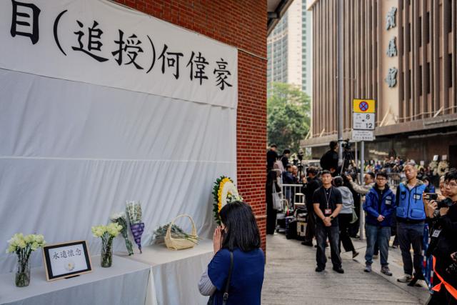People pay their respects to the departing hearse at the funeral for firefighter Ho Wai-ho, who died in the deadly fire at the Wang Fuk Court residential estate in Tai Po district, at the Universal Funeral Parlour in Hung Hom, Hong Kong, on December 19, 2025. (Photo by Leung Man Hei / AFP)