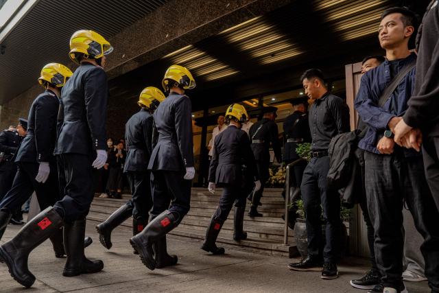 Fire Services Department members are seen at the funeral of the firefighter Ho Wai-ho, who died in the deadly fire at the Wang Fuk Court residential estate in Tai Po district, at the Universal Funeral Parlour in Hung Hom, Hong Kong, on December 19, 2025. (Photo by Leung Man Hei / AFP)