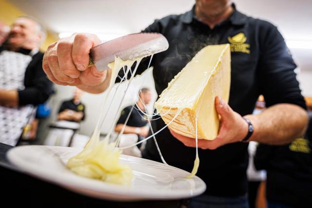 (FILES) A waiter carries raclettes to customers during the first-ever Raclette World Championships featuring local and international raclette cheeses, in Morgins, on October 28, 2023. Long confined to winter weekends and mountain getaways, raclette is now making an appearance at Christmas: convivial, simple, and economical, it’s winning over more and more families looking for a warm meal without breaking the bank. (Photo by VALENTIN FLAURAUD / AFP)