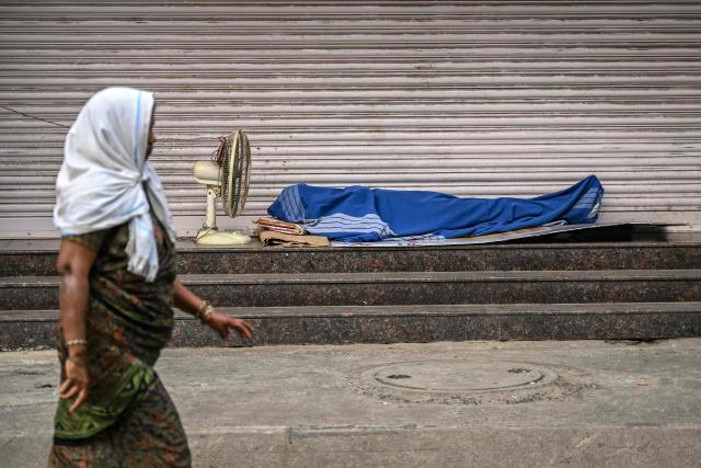 A man sleeps next to a closed shop on a winter morning in Chennai on December 19, 2025. (Photo by R.Satish BABU / AFP)