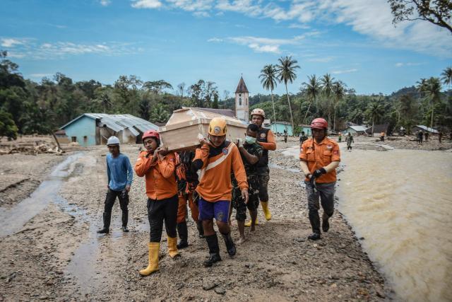 Search and rescue members carry a coffin as they relocate the graves of flash flood victims fearing the graves could be washed away again following heavy rain in Hutanabolon, North Sumatra, on December 18, 2025. The latest government figures issued on December 16 put the death toll of the devastating floods at 1,030 people. Another 205 remain missing in the aftermath of one of the deadliest natural disasters to hit Sumatra's resource-rich Aceh province, the scene of a killer tsunami in 2004. (Photo by Damai Mendrofa / AFP)