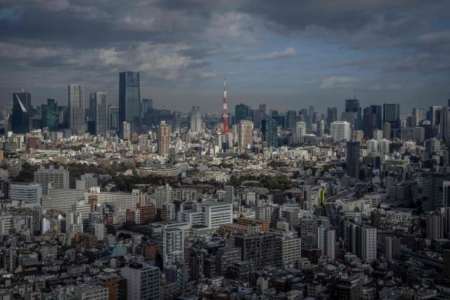 The city skyline is seen as the Tokyo Tower looms in the background in Tokyo on December 19, 2025. (Photo by Yuichi YAMAZAKI / AFP)