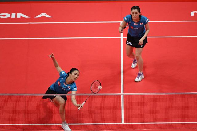 Japan’s Rin Iwanaga (R) and Kie Nakanishi play a point during their women's doubles match against China’s Jia Yifan and Zhang Shuxian at the BWF Badminton World Tour Finals at the Hangzhou Olympic Sports Centre Gymnasium in Hangzhou, in eastern China's Zhejiang province on December 19, 2025. (Photo by Jade Gao / AFP)