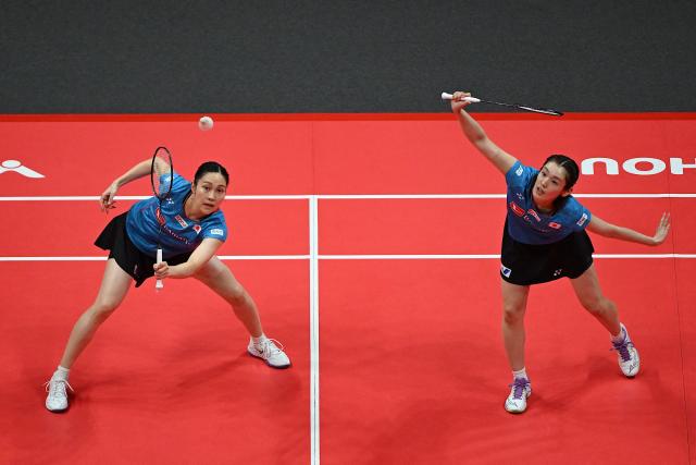Japan’s Rin Iwanaga (R) and Kie Nakanishi play a point during their women's doubles match against China’s Jia Yifan and Zhang Shuxian at the BWF Badminton World Tour Finals at the Hangzhou Olympic Sports Centre Gymnasium in Hangzhou, in eastern China's Zhejiang province on December 19, 2025. (Photo by Jade Gao / AFP)
