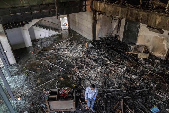 A man walks through the burnt office of The Daily Star newspaper in Dhaka on December 19, 2025, amid protests following the news of the death of youth leader Sharif Osman Hadi. Violence broke out in Bangladesh's capital early on December 19 after a youth leader of the country's 2024 pro-democracy uprising who was injured in an assassination attempt died in a hospital in Singapore. Several buildings in the capital, including those housing the country's two leading newspapers, were set on fire, according to authorities, with staff trapped inside. (Photo by Abdul Goni / AFP)