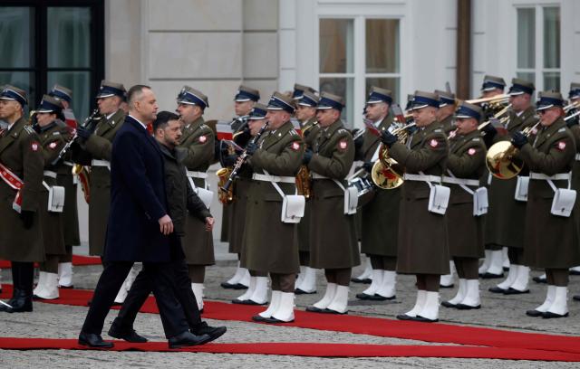 Poland's President Karol Nawrocki (L) and Ukraine's President Volodymyr Zelensky review a military honor guard during a welcome ceremony prior to talks at the Presidential Palace in Warsaw, Poland, on December 19, 2025. (Photo by Wojtek RADWANSKI / AFP)