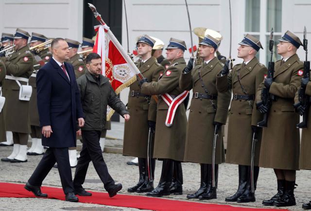 Poland's President Karol Nawrocki (L) and Ukraine's President Volodymyr Zelensky review a military honor guard during a welcome ceremony prior to talks at the Presidential Palace in Warsaw, Poland, on December 19, 2025. (Photo by Wojtek RADWANSKI / AFP)