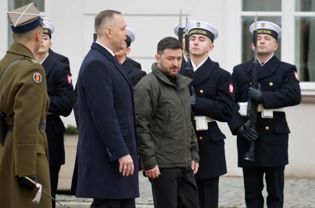 Poland's President Karol Nawrocki (C-L) and Ukraine's President Volodymyr Zelensky (C-R) review a military honor guard during a welcome ceremony prior to talks at the Presidential Palace in Warsaw, Poland, on December 19, 2025. (Photo by Wojtek RADWANSKI / AFP)
