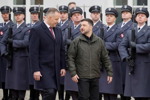Poland's President Karol Nawrocki (C-L) and Ukraine's President Volodymyr Zelensky (C-R) review a military honor guard during a welcome ceremony prior to talks at the Presidential Palace in Warsaw, Poland, on December 19, 2025. (Photo by Wojtek RADWANSKI / AFP)