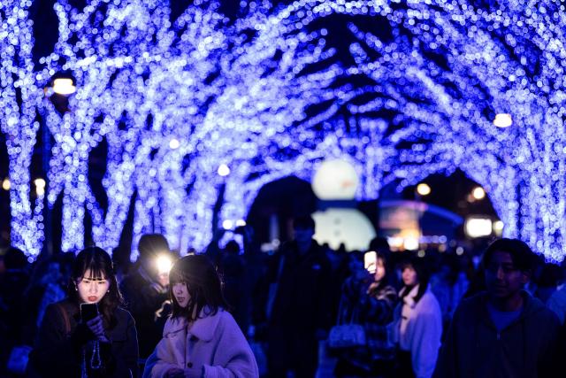 People take pictures with festive light installations ahead of Christmas in Tokyo's Shibuya district on December 19, 2025. (Photo by Philip FONG / AFP)