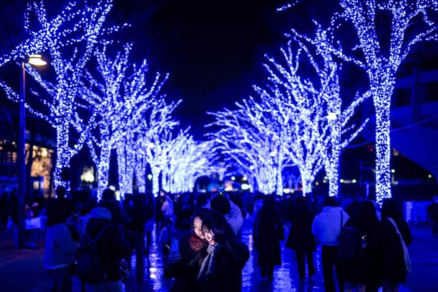 People take pictures with festive light installations ahead of Christmas in Tokyo's Shibuya district on December 19, 2025. (Photo by Philip FONG / AFP)