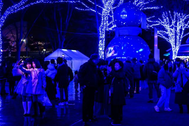 People take pictures with festive light installations ahead of Christmas in Tokyo's Shibuya district on December 19, 2025. (Photo by Philip FONG / AFP)