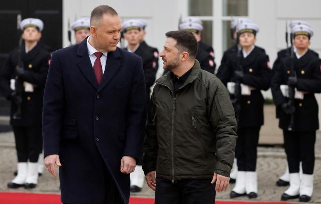 Poland's President Karol Nawrocki (C-L) and Ukraine's President Volodymyr Zelensky (C-R) review a military honor guard during a welcome ceremony prior to talks at the Presidential Palace in Warsaw, Poland, on December 19, 2025. (Photo by Wojtek RADWANSKI / AFP)