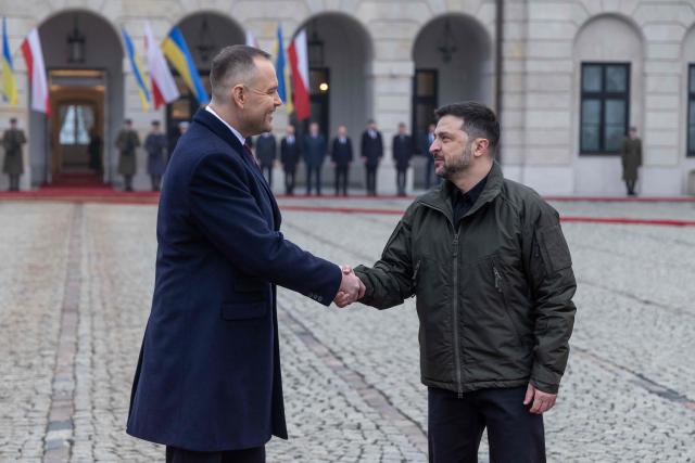 Poland's President Karol Nawrocki (L) and Ukraine's President Volodymyr Zelensky (R) shake hands during a welcome ceremony prior to talks at the Presidential Palace in Warsaw, Poland, on December 19, 2025. (Photo by Wojtek RADWANSKI / AFP)