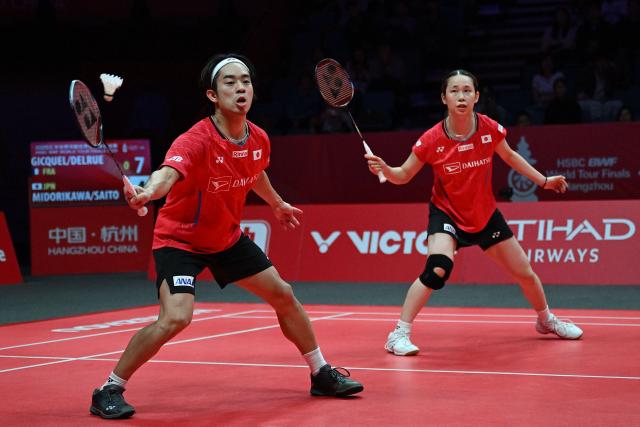 Japan’s Hiroki Midorikawa (L) and Natsu Saito play a point during their mixed doubles match against France’s Thom Gicquel and Delphine Delrue at the BWF Badminton World Tour Finals at the Hangzhou Olympic Sports Centre Gymnasium in Hangzhou, in eastern China's Zhejiang province on December 19, 2025. (Photo by Jade Gao / AFP)