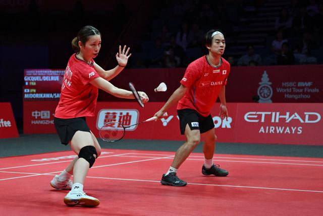 Japan’s Hiroki Midorikawa and Natsu Saito (L) play a point during their mixed doubles match against France’s Thom Gicquel and Delphine Delrue at the BWF Badminton World Tour Finals at the Hangzhou Olympic Sports Centre Gymnasium in Hangzhou, in eastern China's Zhejiang province on December 19, 2025. (Photo by Jade Gao / AFP)