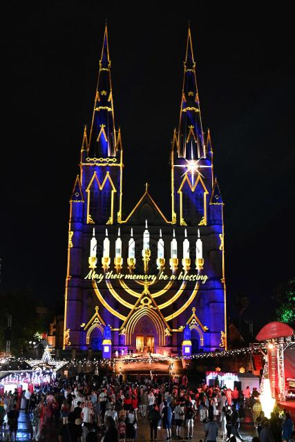 Sydney’s St. Mary’s Cathedral is illuminated with a menorah during a light show on December 19, 2025, in tribute to victims of the Bondi attack. A young girl and Holocaust survivors were among 15 people shot and killed allegedly by a father and his son at a Jewish Hanukkah festival gathering on Australia's Bondi Beach. (Photo by Saeed KHAN / AFP)