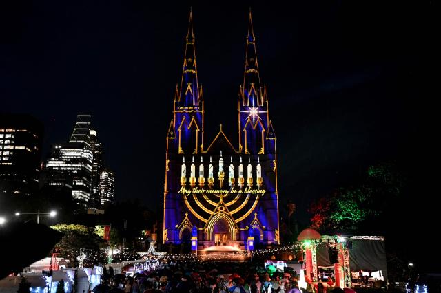 Sydney’s St. Mary’s Cathedral is illuminated with a menorah during a light show on December 19, 2025, in tribute to victims of the Bondi attack. A young girl and Holocaust survivors were among 15 people shot and killed allegedly by a father and his son at a Jewish Hanukkah festival gathering on Australia's Bondi Beach. (Photo by Saeed KHAN / AFP)