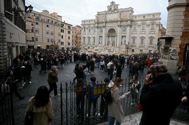 Tourists walk around the Trevi fountain in central Rome on December 19, 2025. (Photo by Filippo MONTEFORTE / AFP)