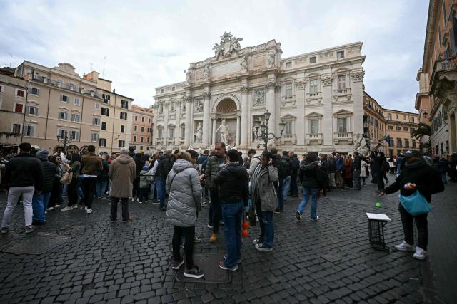 Tourists walk around the Trevi fountain in central Rome on December 19, 2025. (Photo by Filippo MONTEFORTE / AFP)