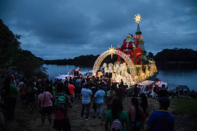 Riverine residents watch the arrival of a ferry decorated for Christmas in the community of Bela Vista do Jaraqui, on the Rio Negro in the rural area of Manaus, Amazonas state, northern Brazil on December 18, 2025. ‘Natal nas Aguas’ (Christmas on the Waters) is an initiative that brings the magic of Christmas to riverside communities in hard-to-reach locations. (Photo by MICHAEL DANTAS / AFP)