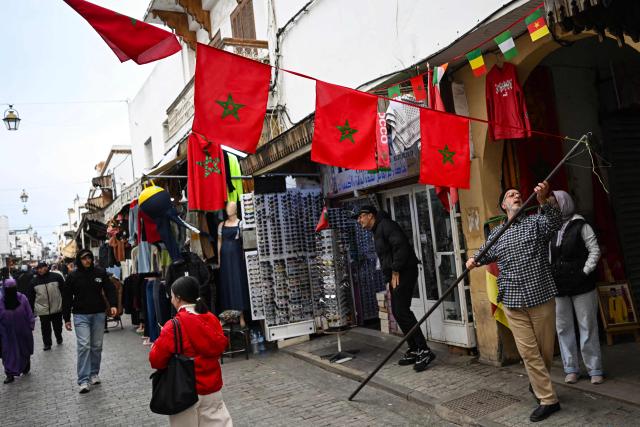 A man installs Moroccan flags in a pedestrian street in Rabat, on December 19, 2025, ahead of the Africa Cup of Nations (AFCON) (Photo by Paul ELLIS / AFP)